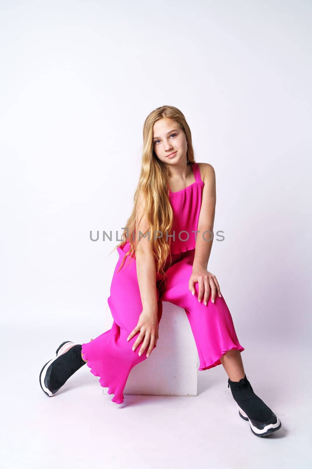 Young girl posing in a pink suit on a white background sitting by EkaterinaPereslavtseva