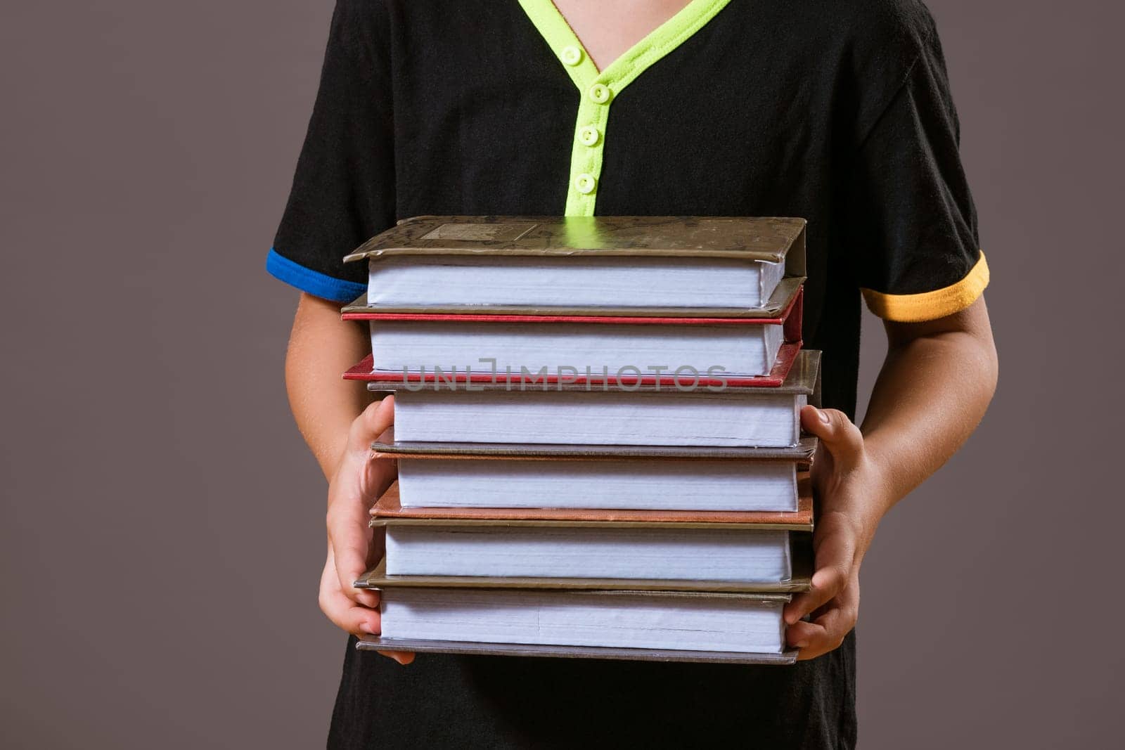 schoolboy boy holding a stack of books on a gray background by EkaterinaPereslavtseva