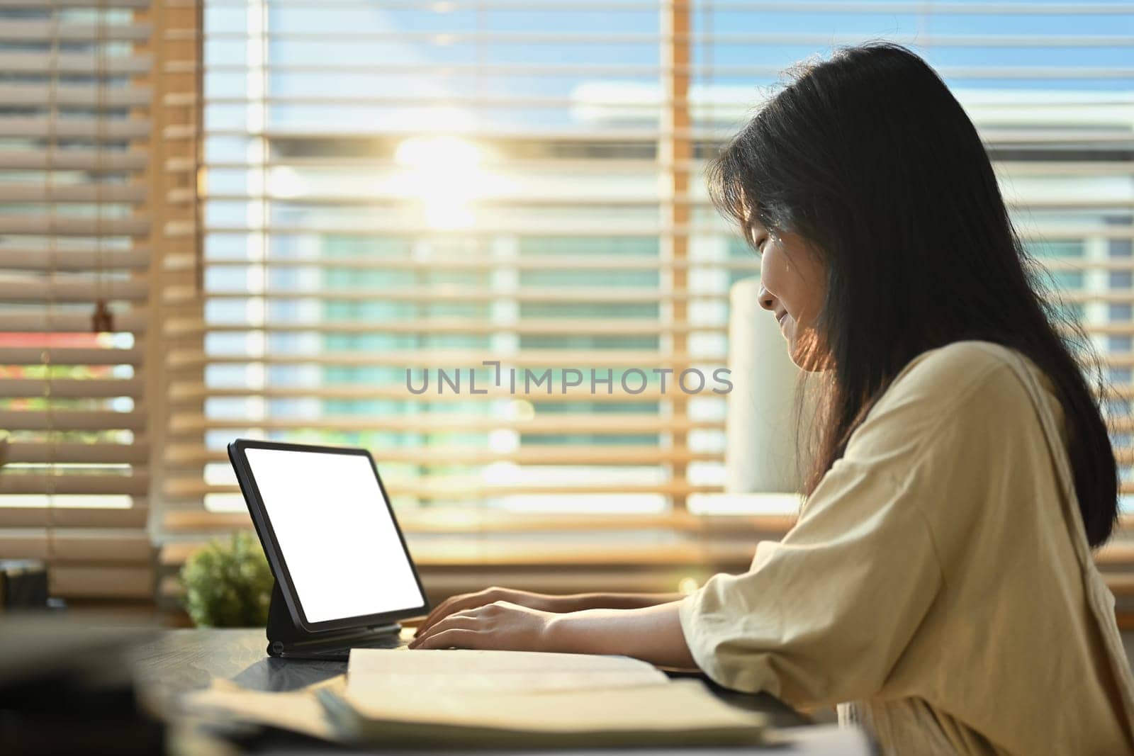 Smiling teenage girl using digital tablet, studying remotely at home. Homeschooling, online education, e-learning concept.