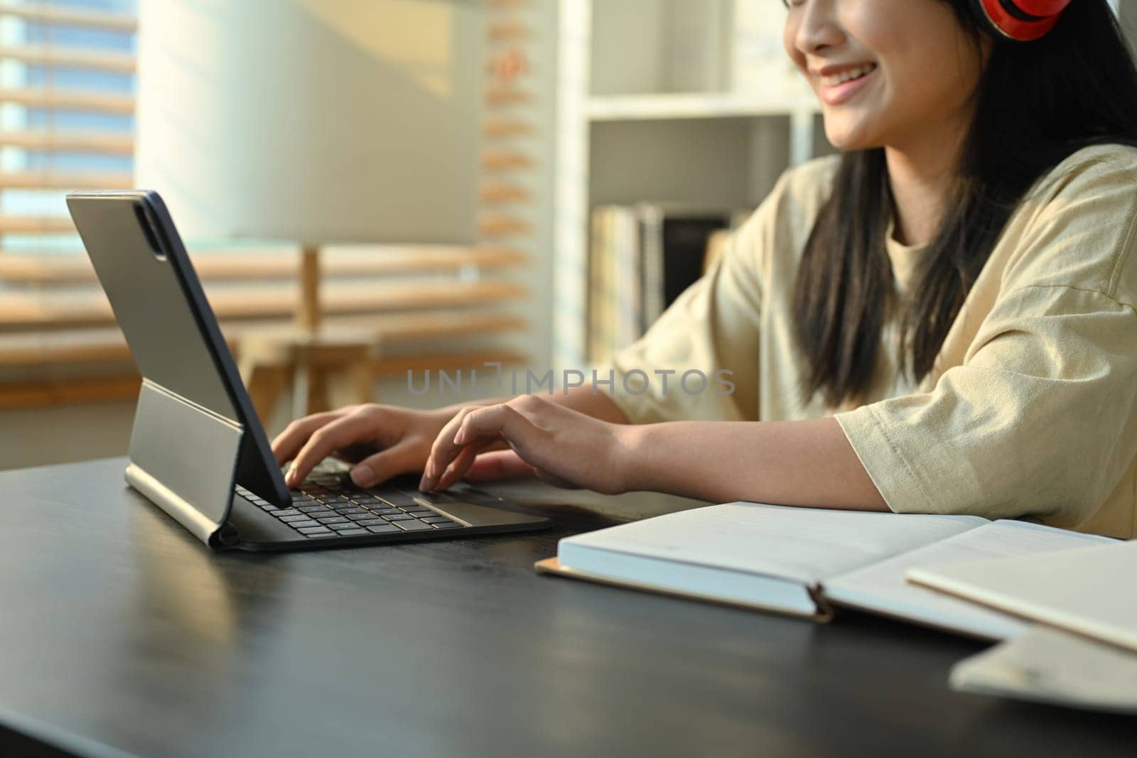 Happy teenaged girl using digital tablet, listening to online lecture. Homeschooling, online education, e-learning by prathanchorruangsak