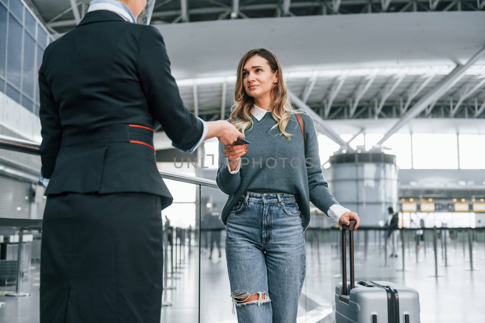 With documents. Young female tourist is in the airport at daytime.