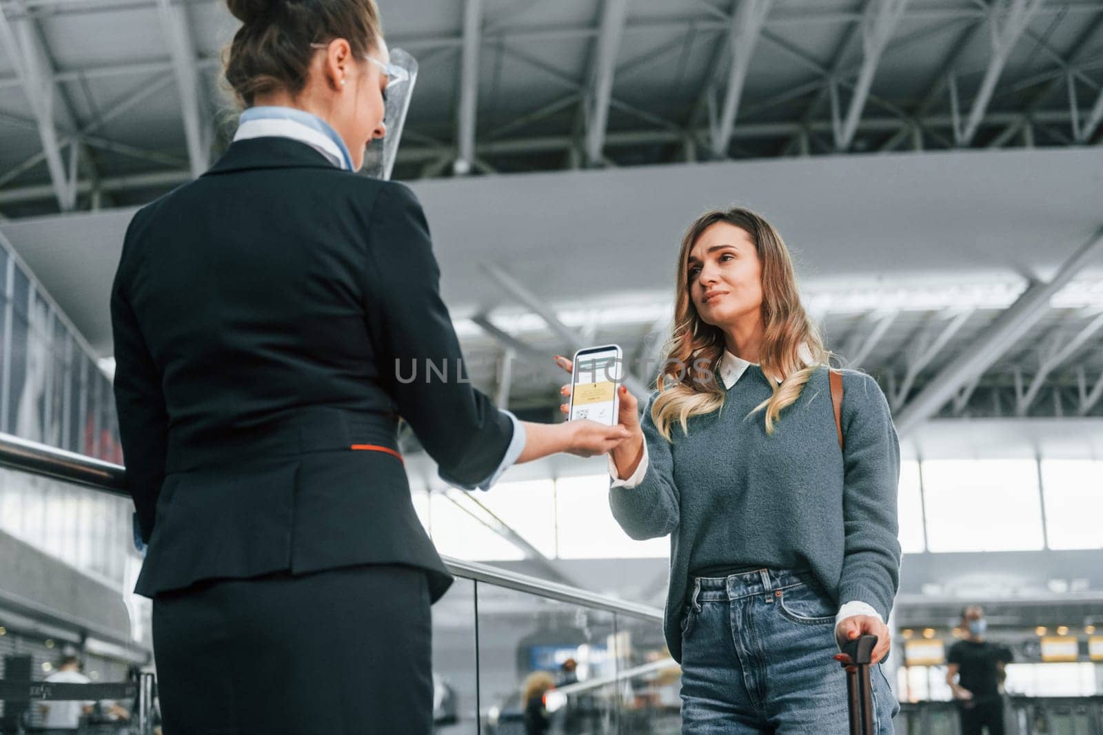 Vaccination certificate in the phone. Young female tourist is in the airport at daytime.