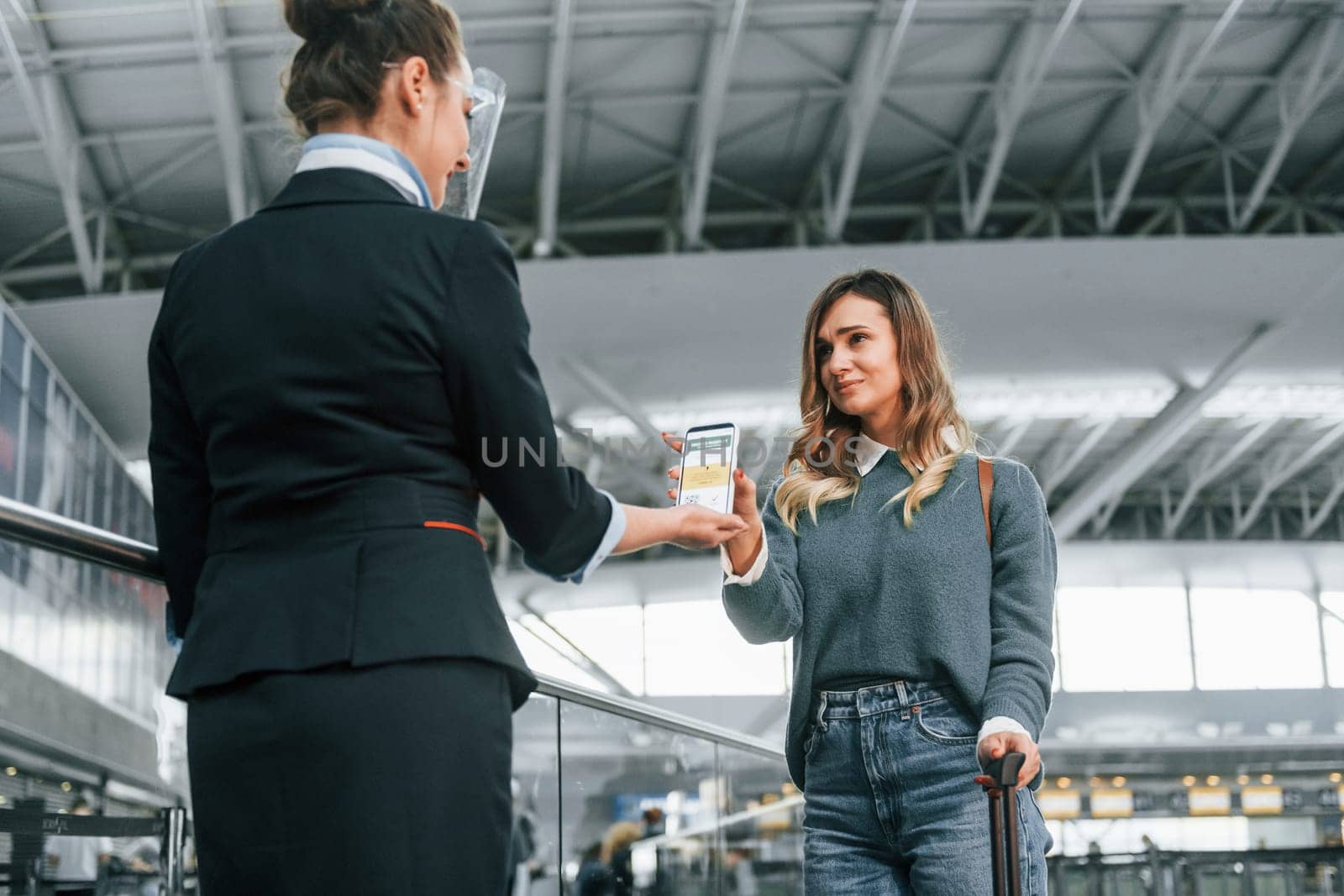 Vaccination certificate in the phone. Young female tourist is in the airport at daytime.