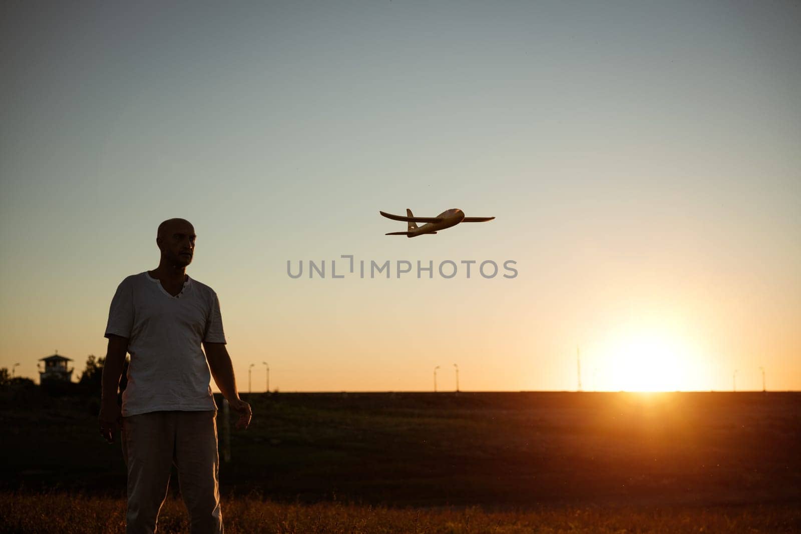 Soft focus of father and son playing toy airplane in meadow at sunset with happy emotions. Family, vacation and travel concept. At sunset in summer they launch an airplane against background sky