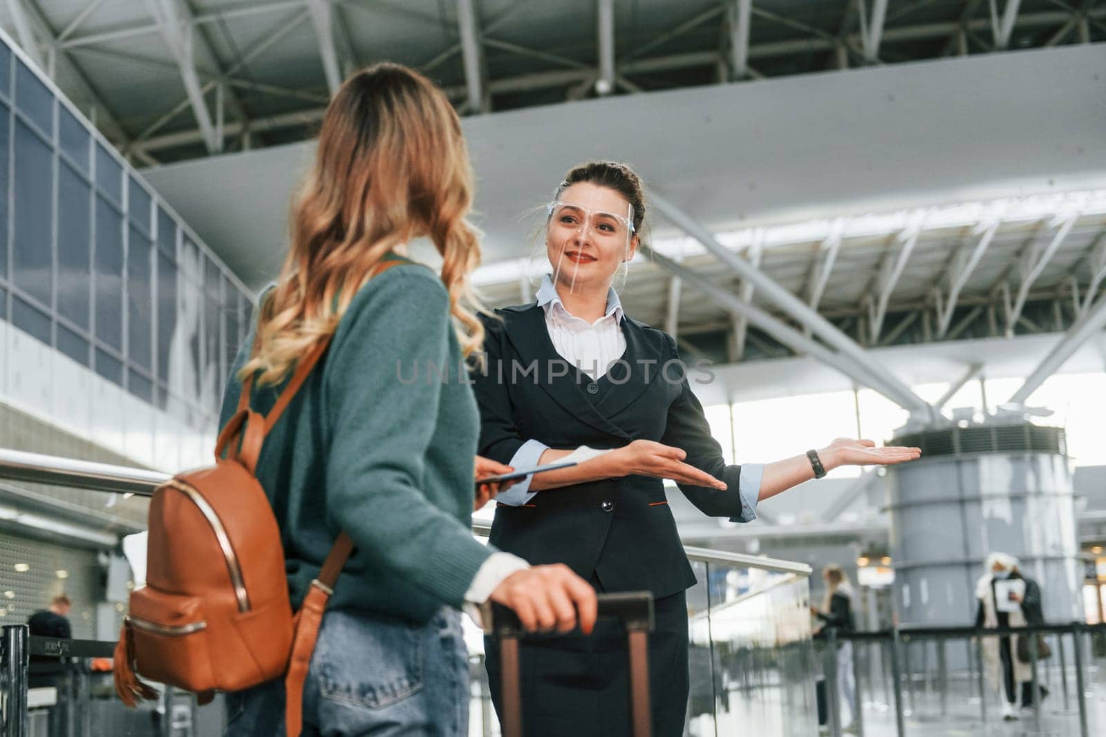 Assistance by woman in formal clothes. Young female tourist is in the airport at daytime.