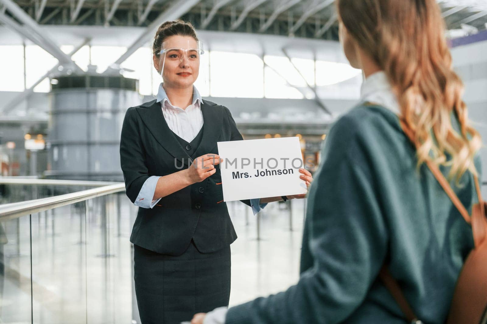 Assistance by woman in formal clothes. Young female tourist is in the airport at daytime by Standret