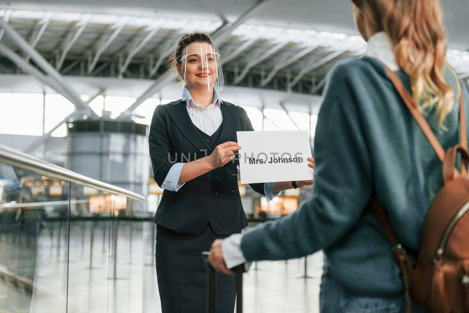 Assistance by woman in formal clothes. Young female tourist is in the airport at daytime by Standret