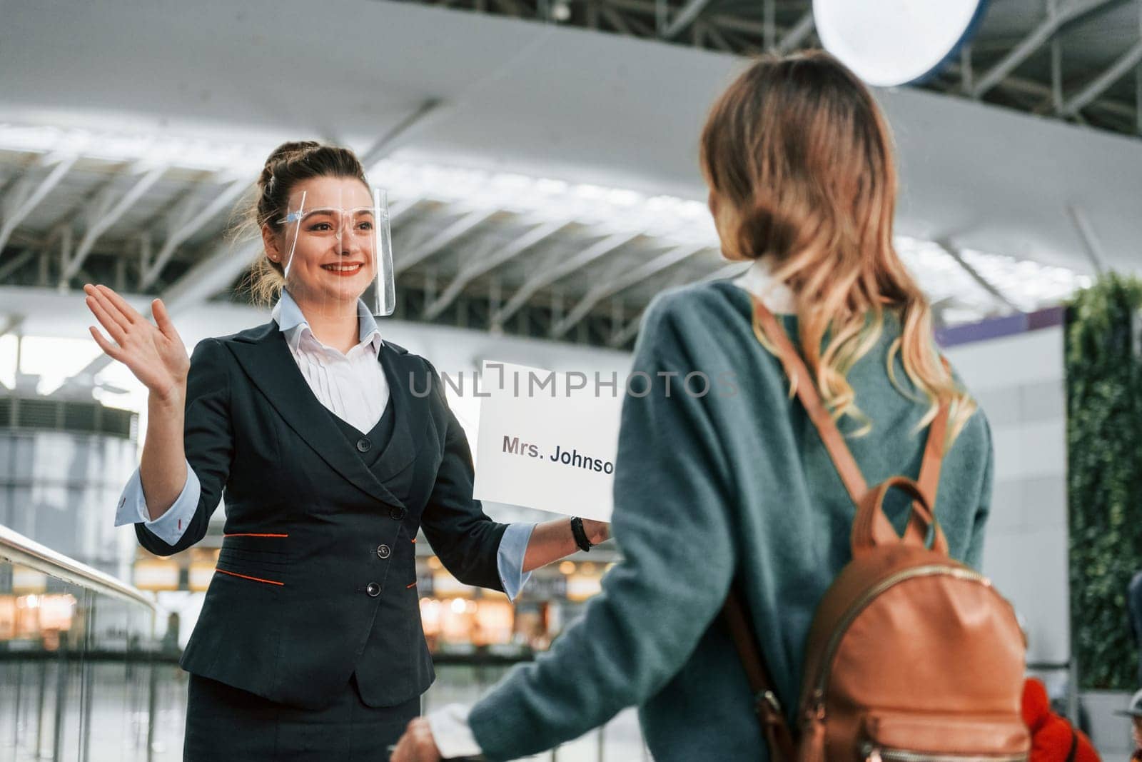 Woman with plate with text. Young female tourist is in the airport at daytime.