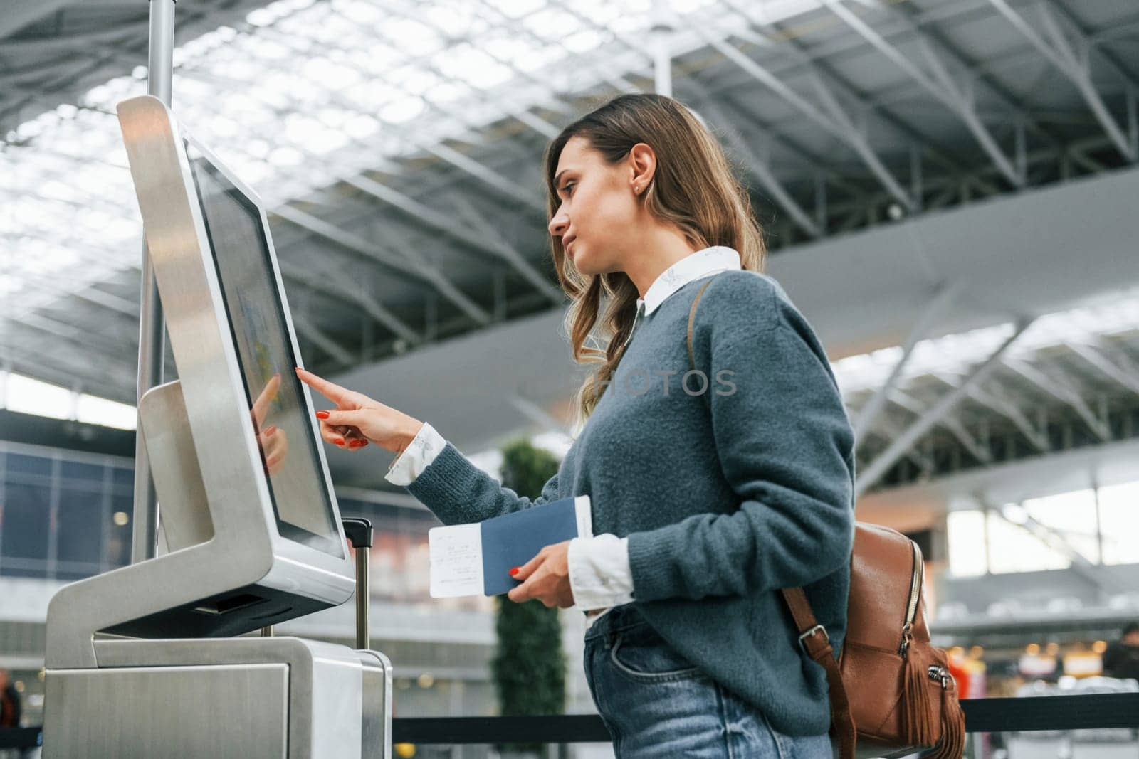 Using terminal. Young female tourist is in the airport at daytime.