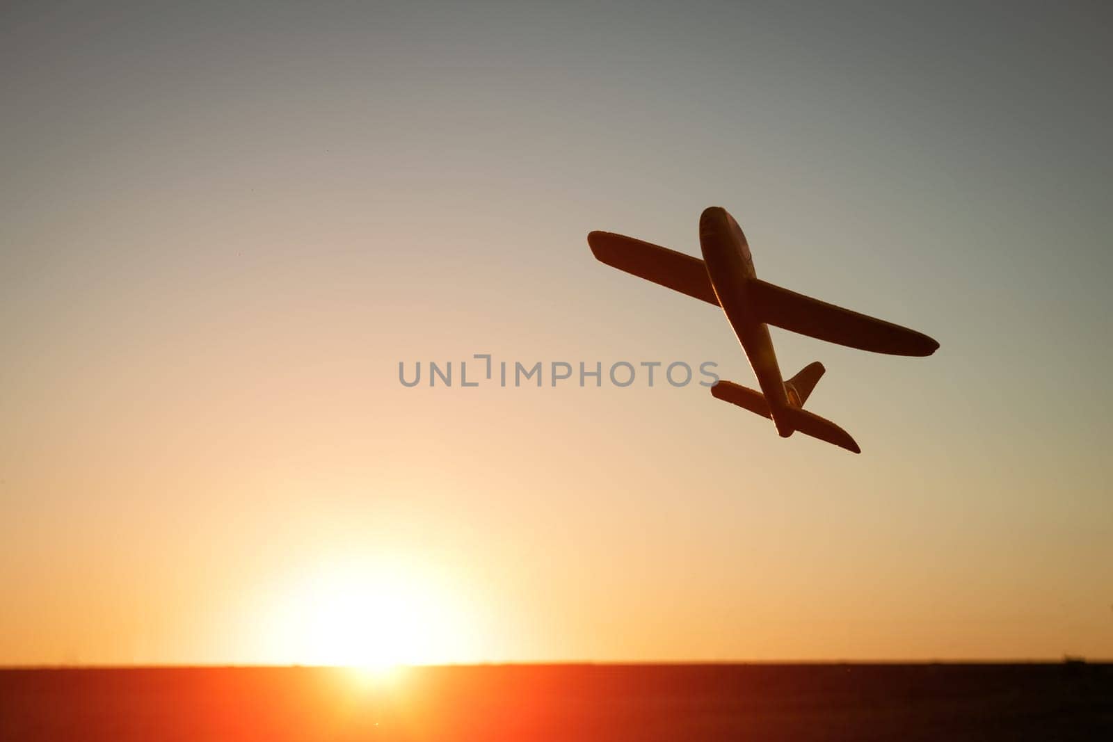Silhouette of an airplane at sunset. Toy plane against the backdrop of the sunset sky. Vacation and travel concept