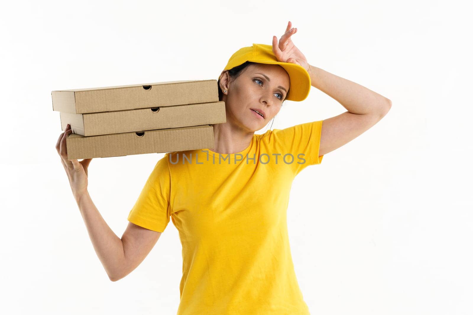 A pizza delivery woman of Caucasian appearance in a yellow uniform, holding cardboard boxes in her hands on a white background.