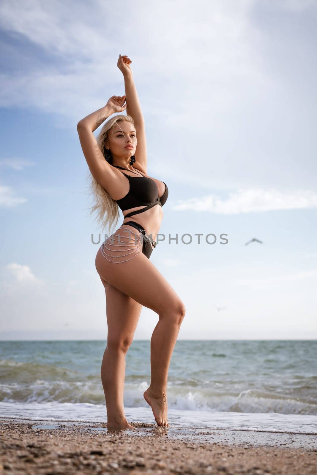 Slender woman posing while standing on the beach in a black swimsuit by EkaterinaPereslavtseva