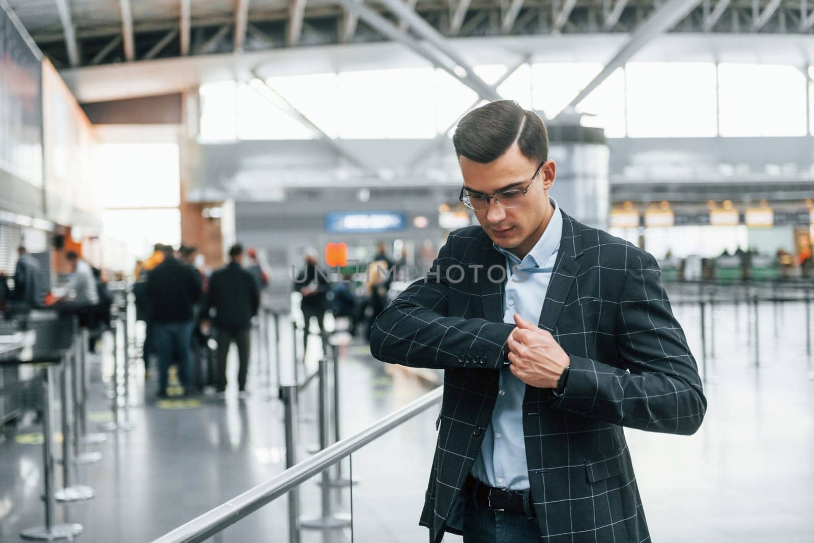 Taking out the documents. Young businessman in formal clothes is in the airport at daytime.