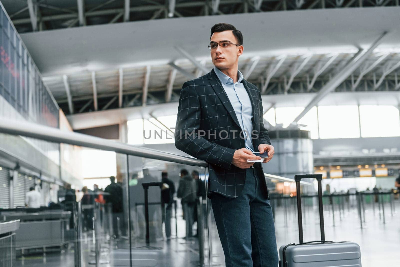 Front view. Young businessman in formal clothes is in the airport at daytime by Standret