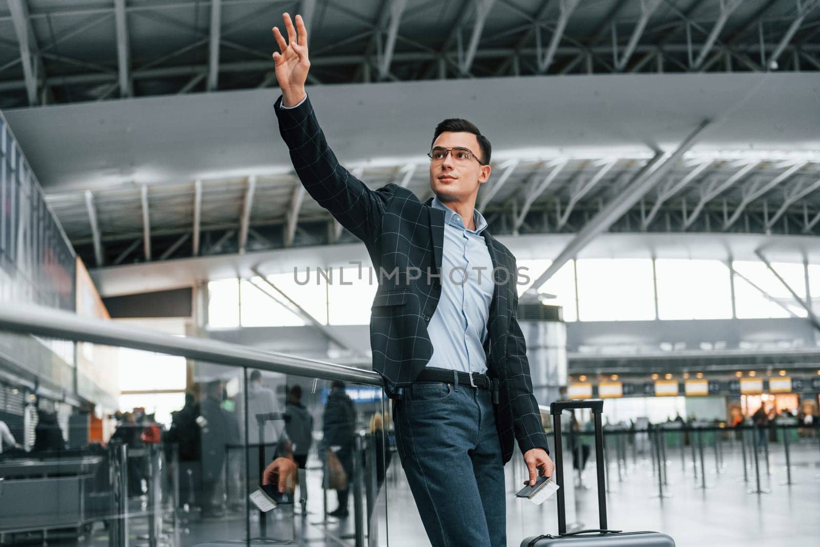 Front view. Young businessman in formal clothes is in the airport at daytime by Standret