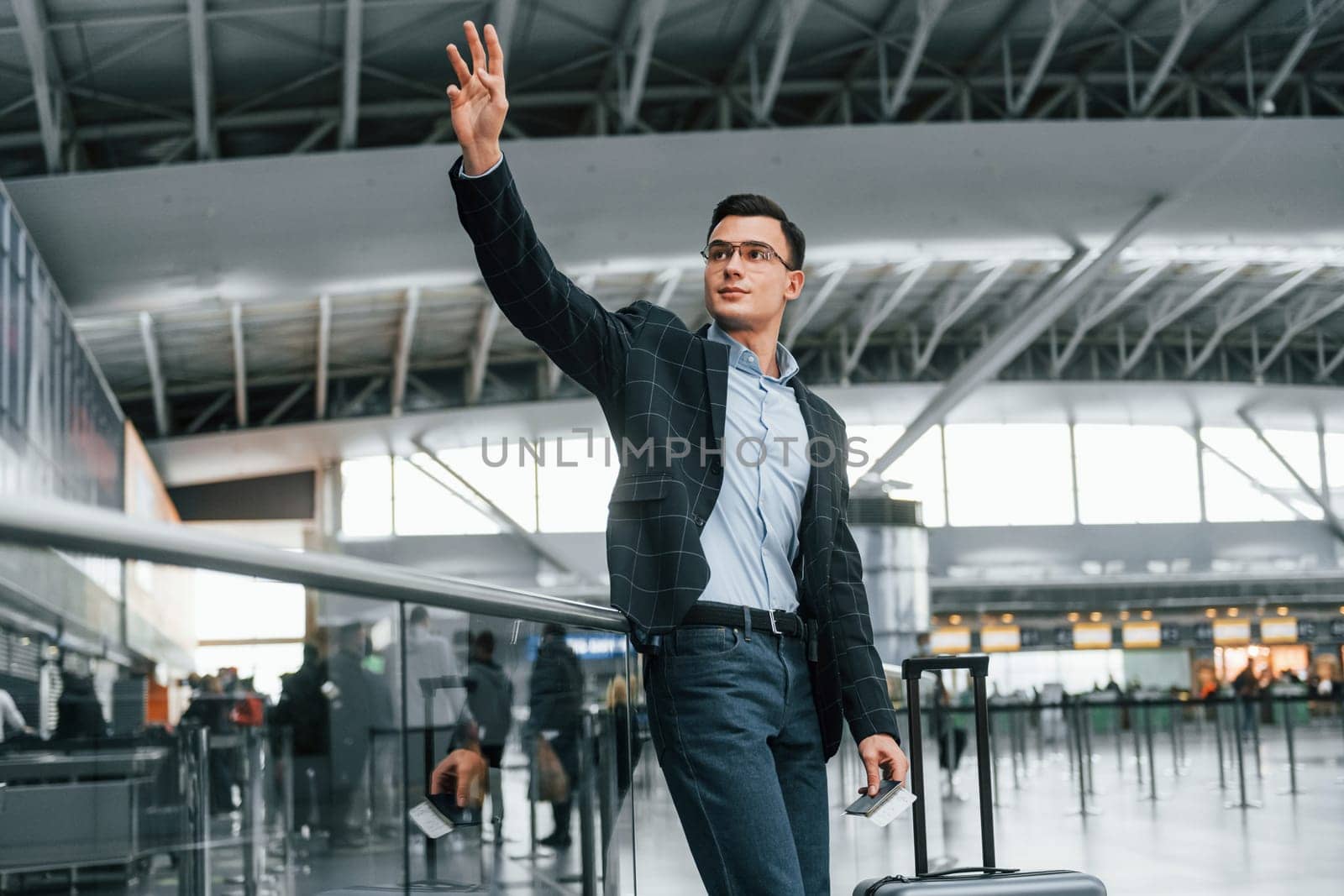 Front view. Young businessman in formal clothes is in the airport at daytime.