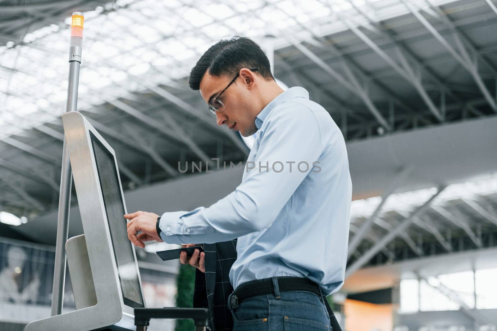 Standing by the terminal. Young businessman in formal clothes is in the airport at daytime by Standret