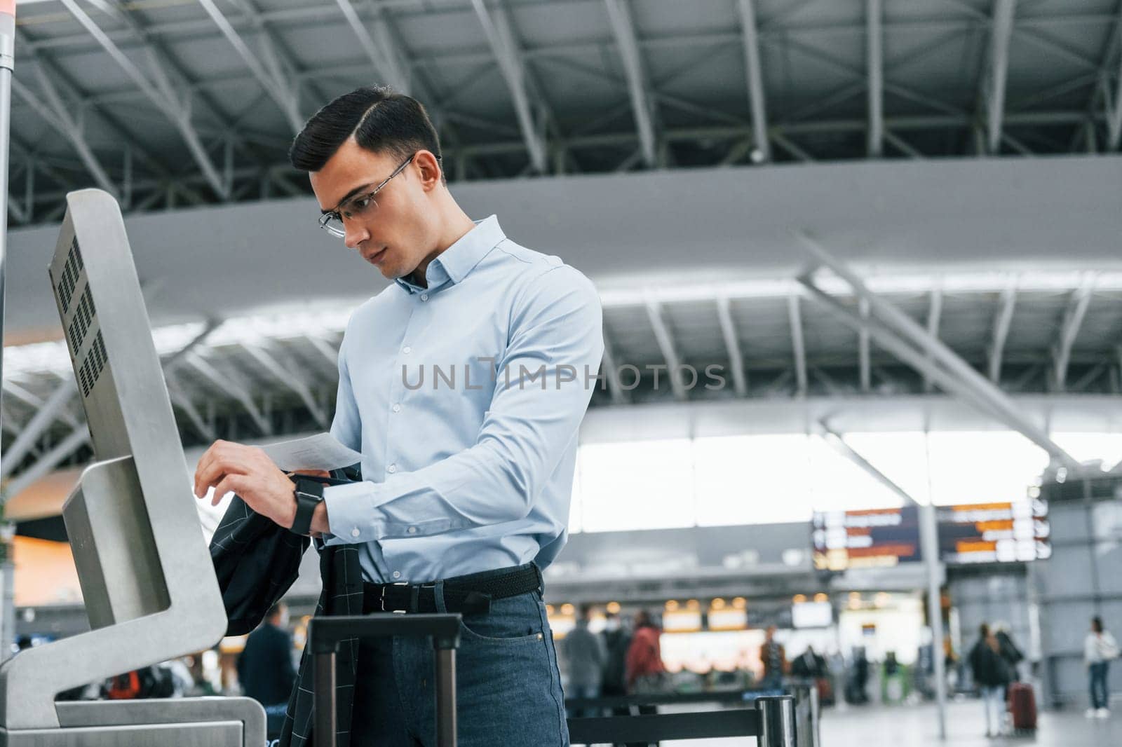 Standing by the terminal. Young businessman in formal clothes is in the airport at daytime by Standret