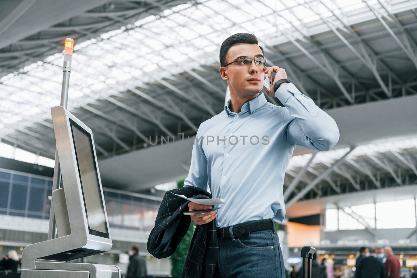 Standing by the terminal. Young businessman in formal clothes is in the airport at daytime.