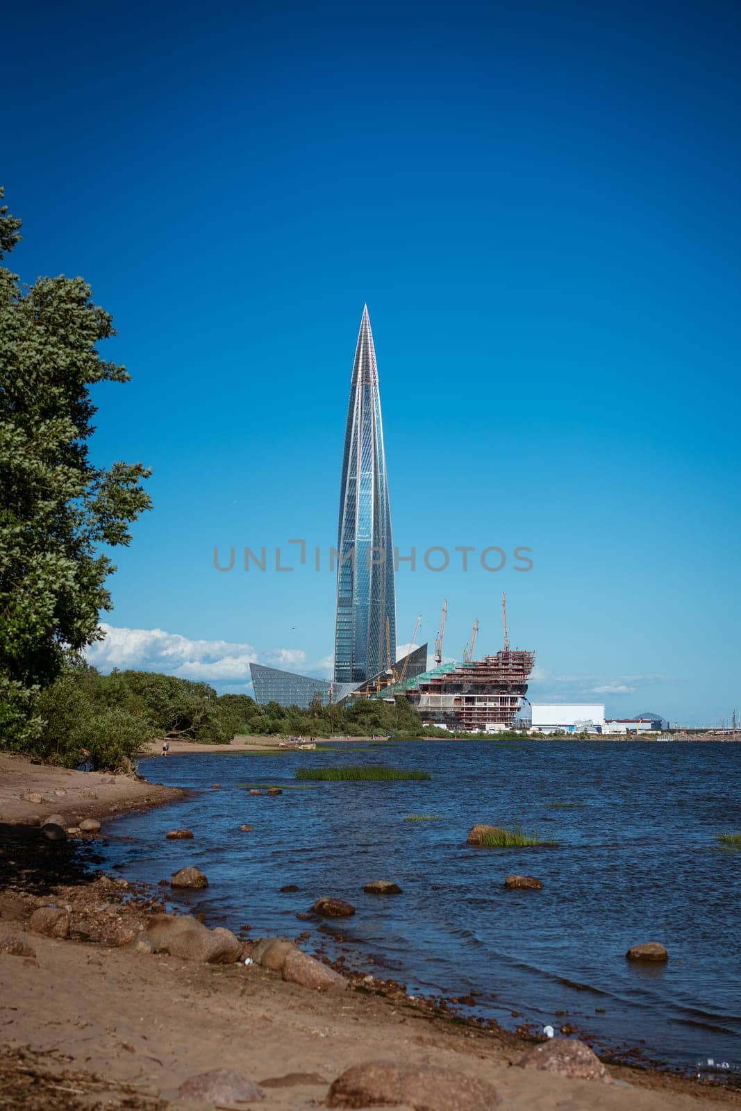beautiful tall building on the shore of the bay, glass facade against the blue sky. Architecture in the city