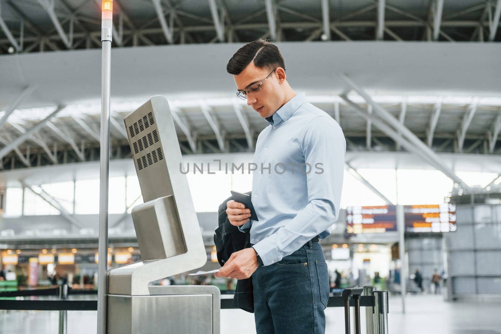 Using terminal. Young businessman in formal clothes is in the airport at daytime by Standret