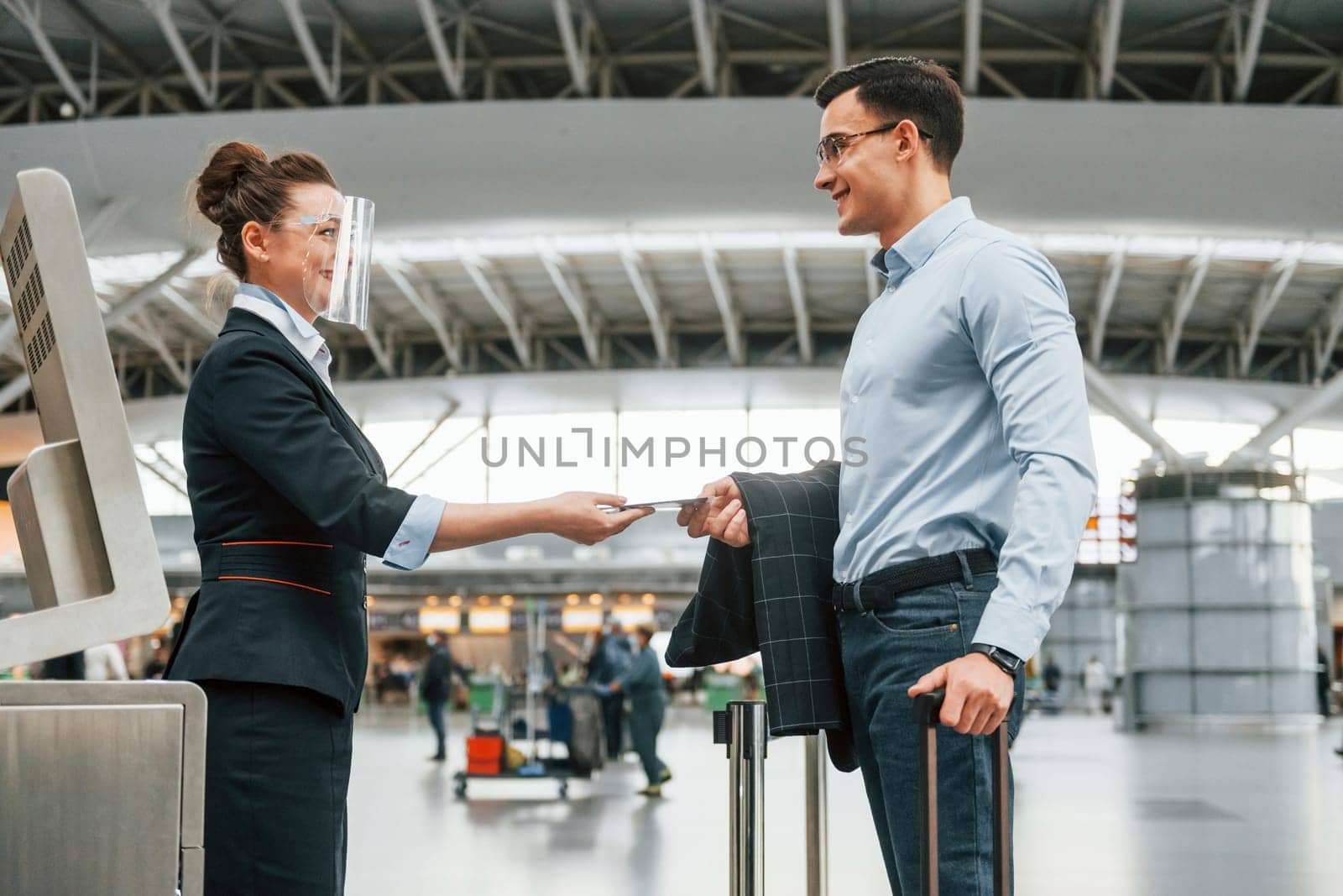 Checking documents. Young businessman in formal clothes is in the airport at daytime.
