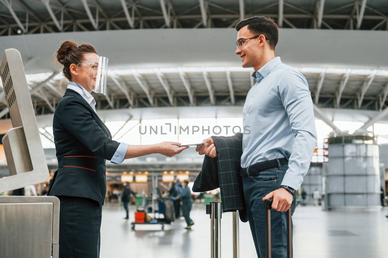 Checking documents. Young businessman in formal clothes is in the airport at daytime by Standret