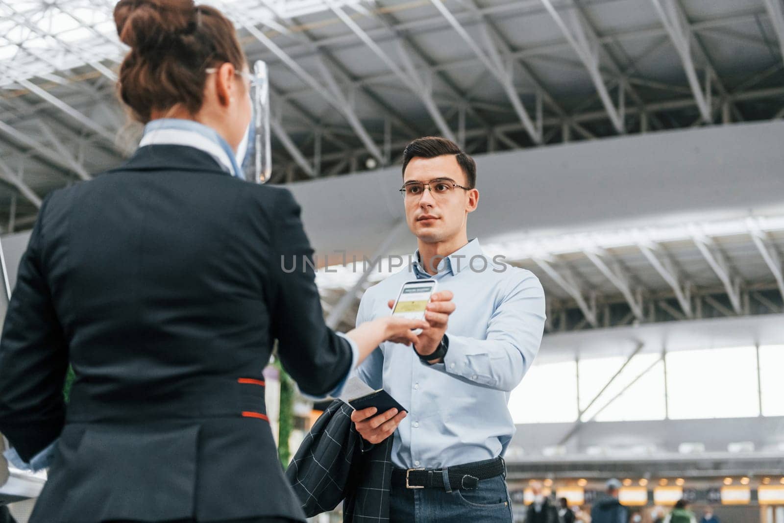 Man showing vaccination certificate. Young businessman in formal clothes is in the airport at daytime by Standret