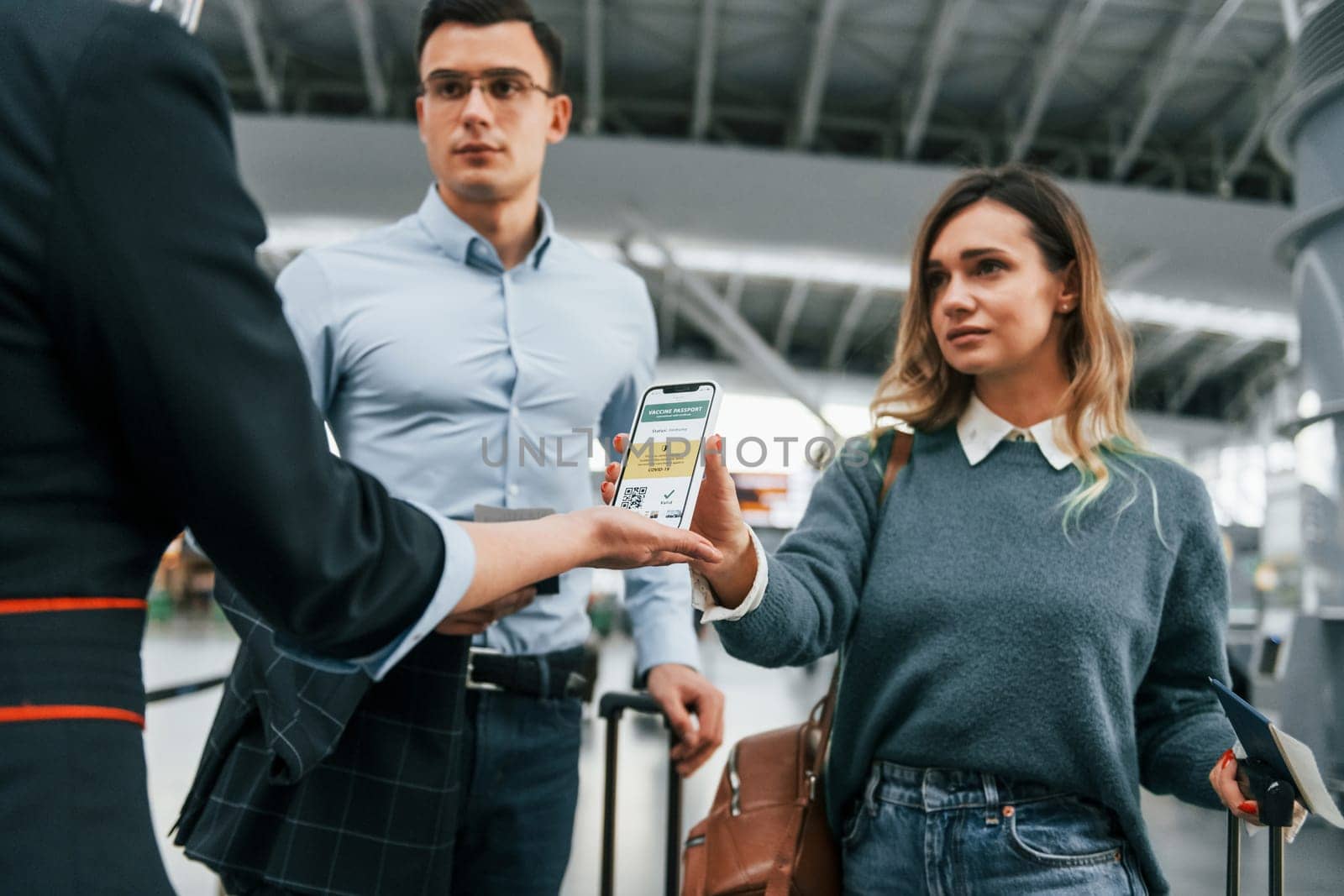 Showing vaccination certificate. Young couple is in the airport together.