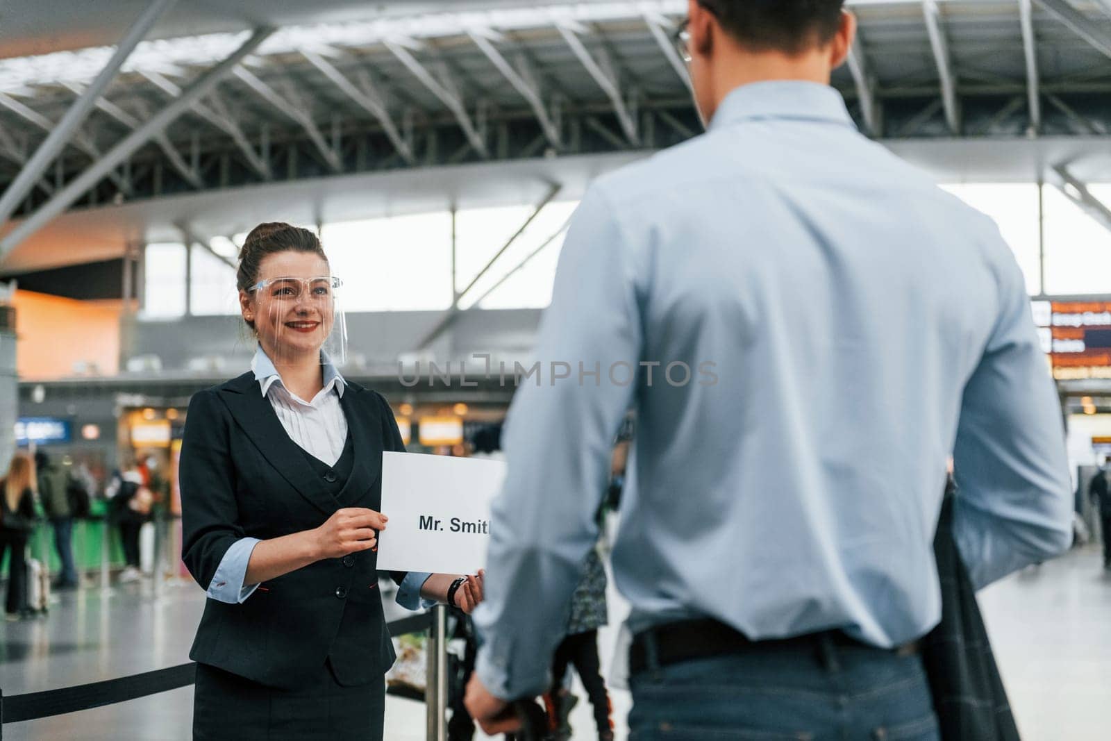 Meet by the woman with text. Young businessman in formal clothes is in the airport at daytime by Standret