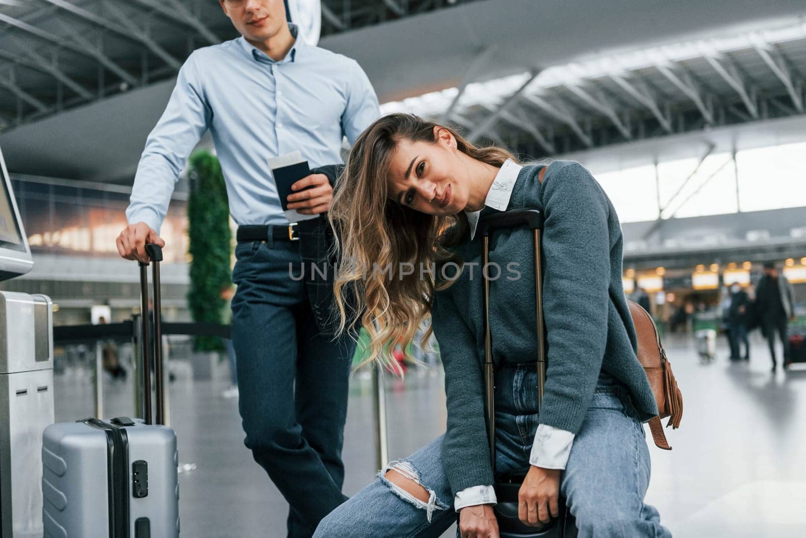 Woman is tired. Young couple is in the airport together by Standret