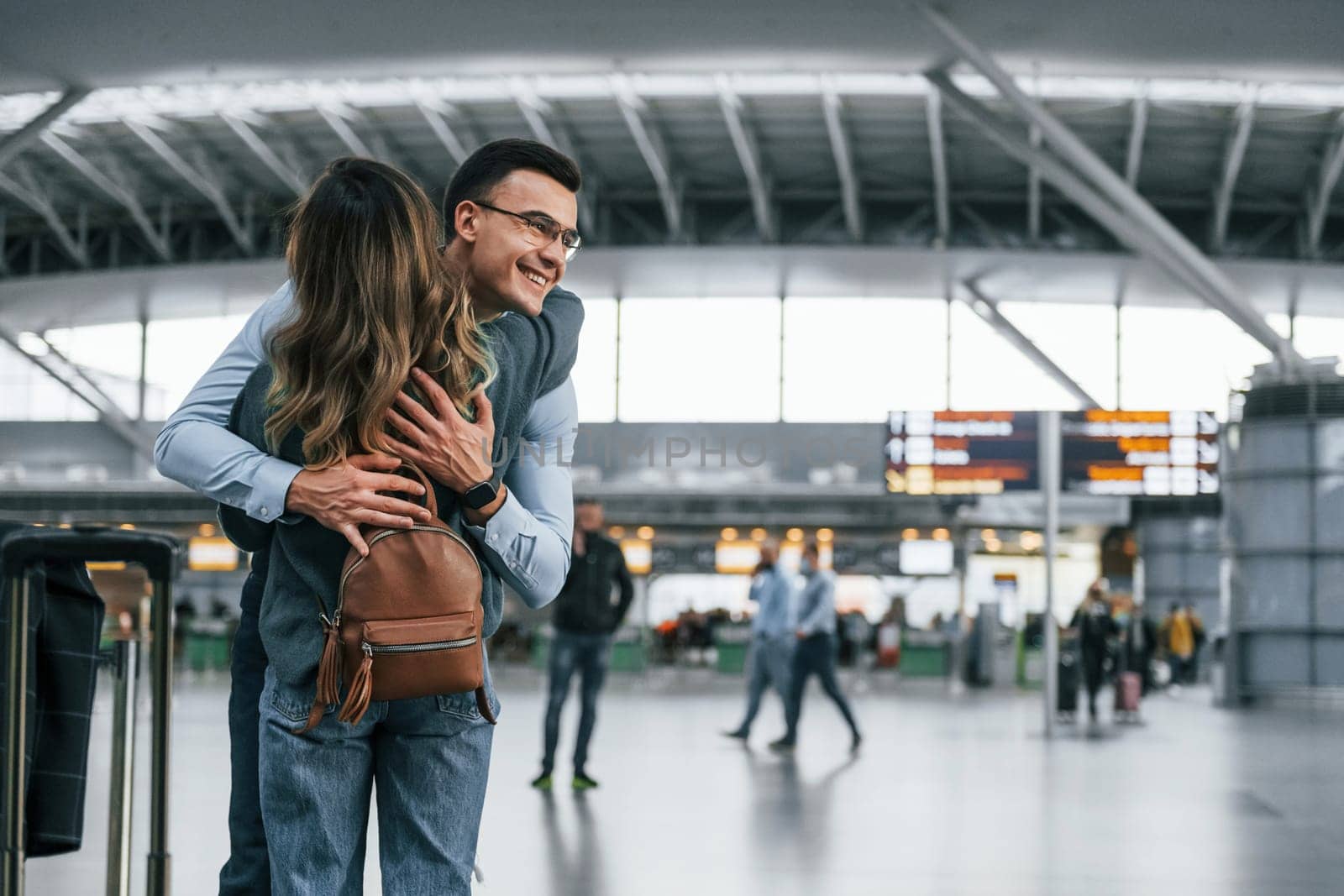 Happy young couple is in the airport together by Standret