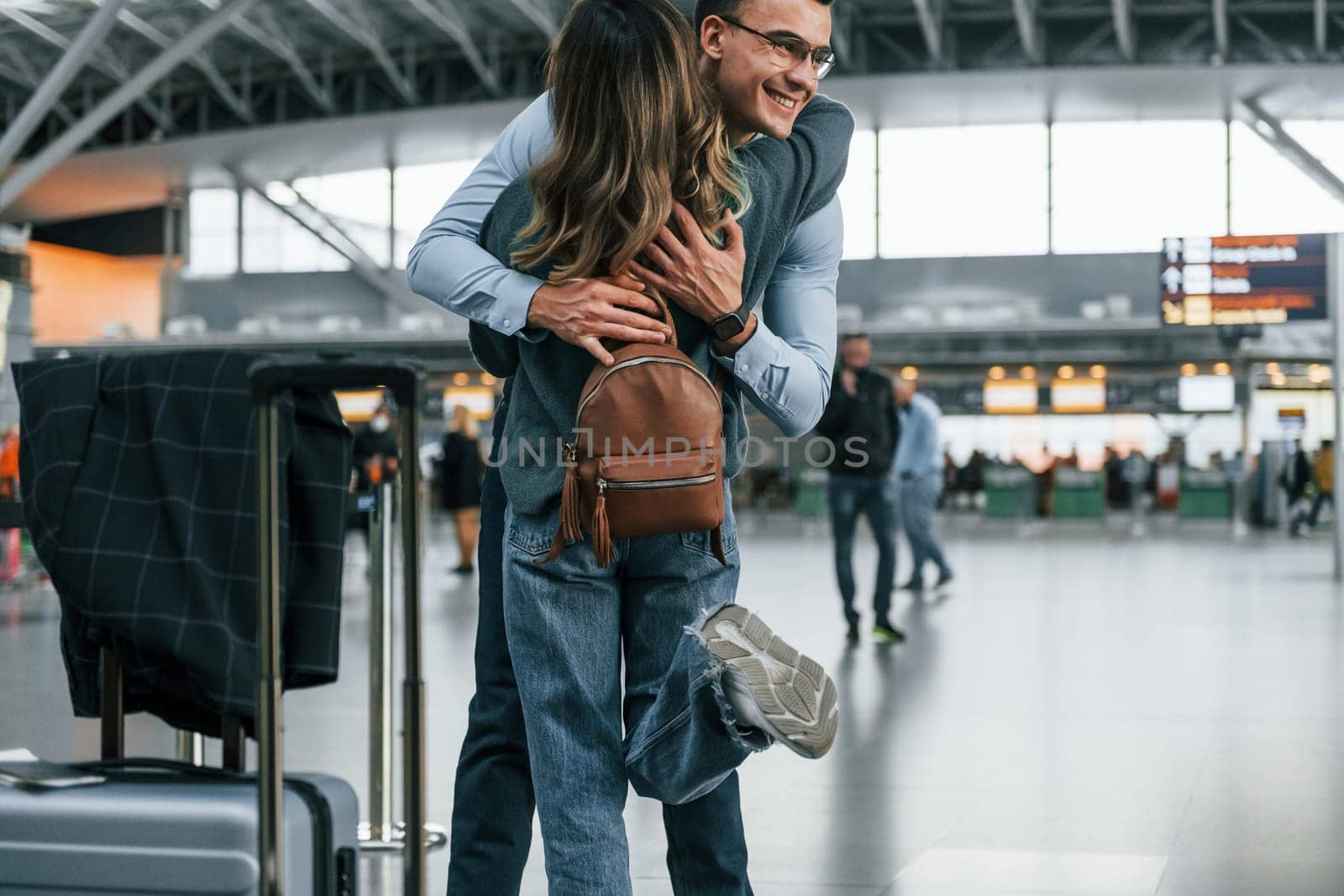 Happy young couple is in the airport together by Standret
