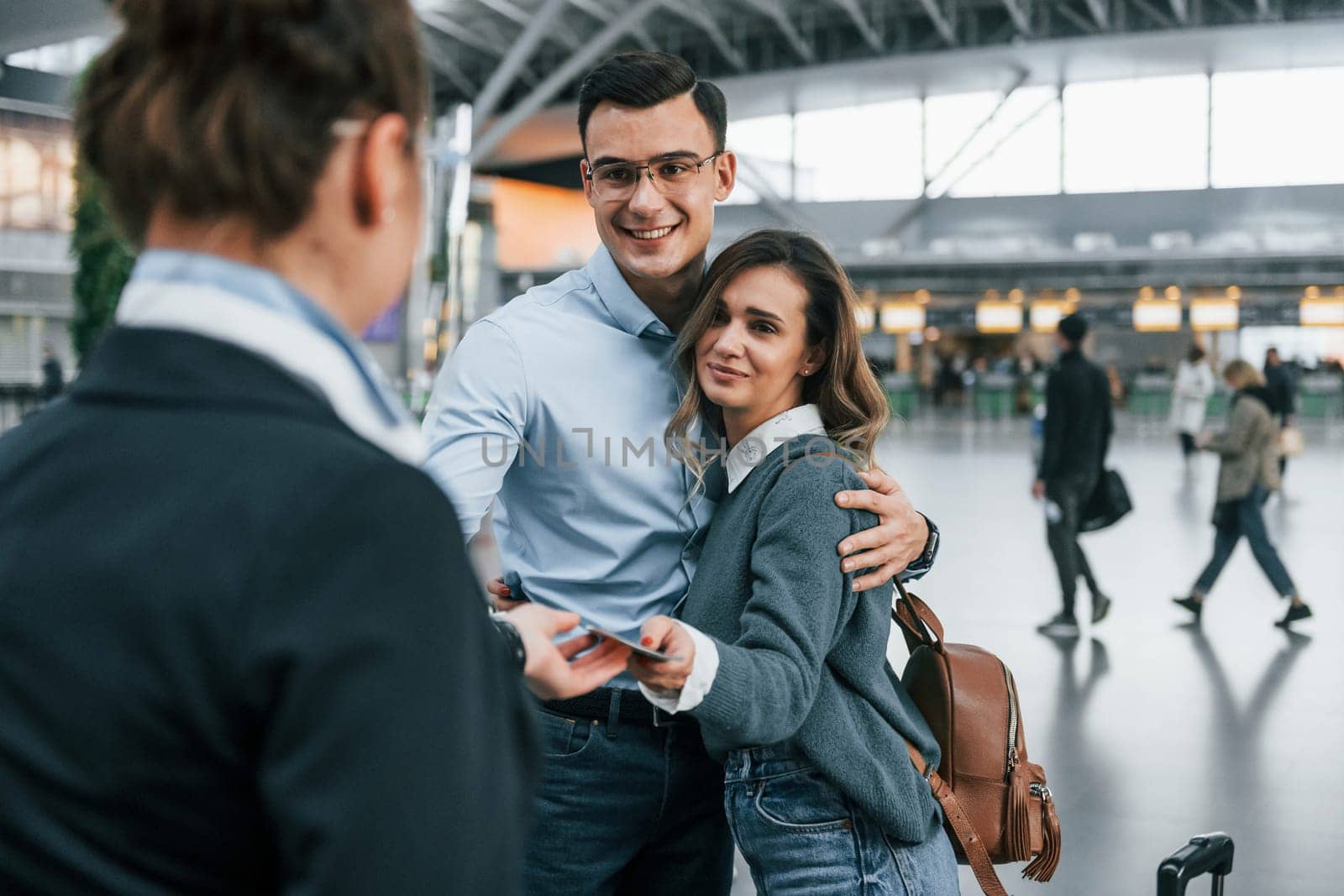 Employee checking the documents. Young couple is in the airport together.