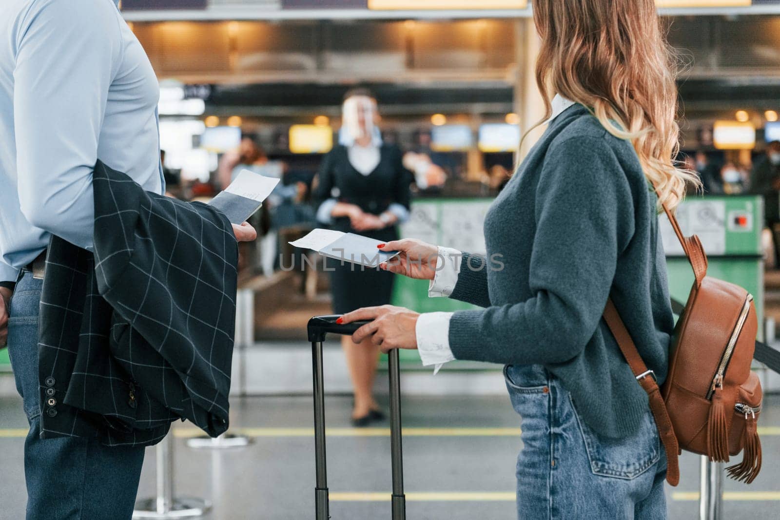 Looking at the employee. Young couple is in the airport together.