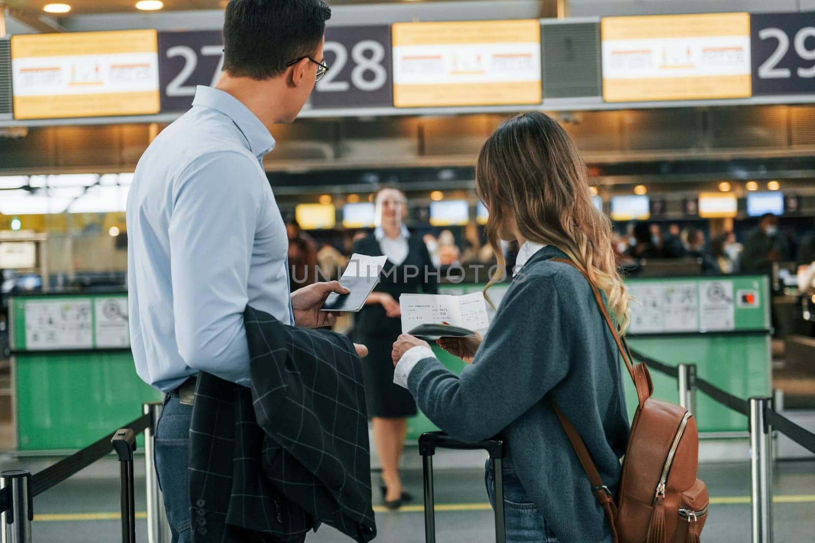 Looking at the employee. Young couple is in the airport together.