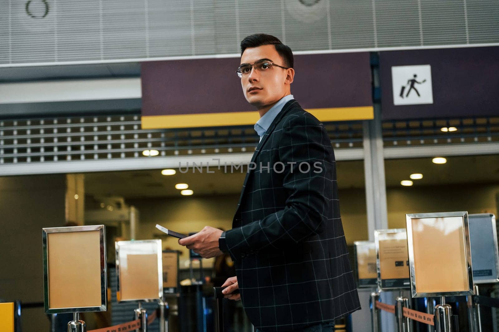 Modern background. Young businessman in formal clothes is in the airport at daytime.