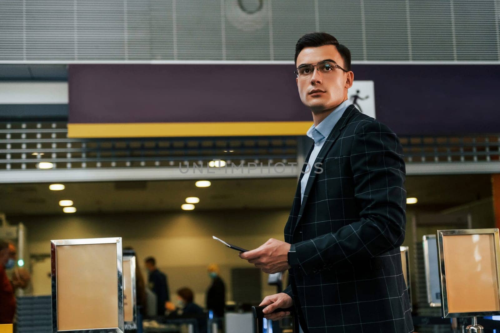 Modern background. Young businessman in formal clothes is in the airport at daytime.