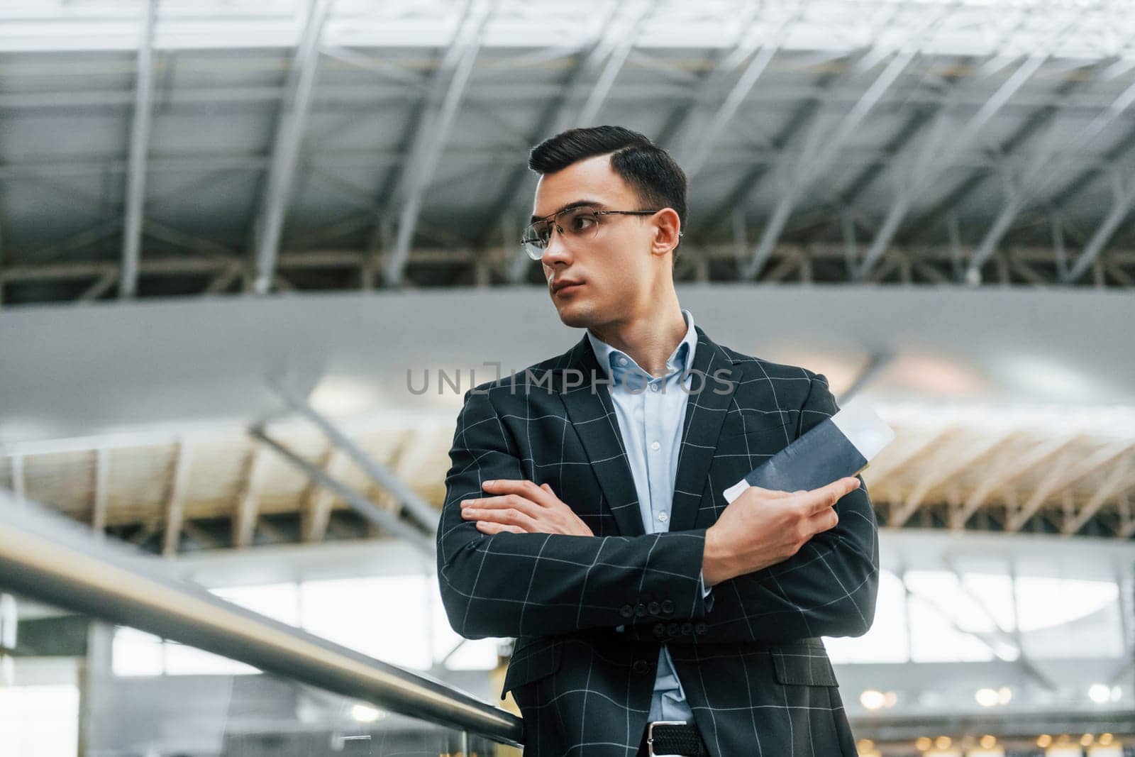 Serious look. Young businessman in formal clothes is in the airport at daytime.