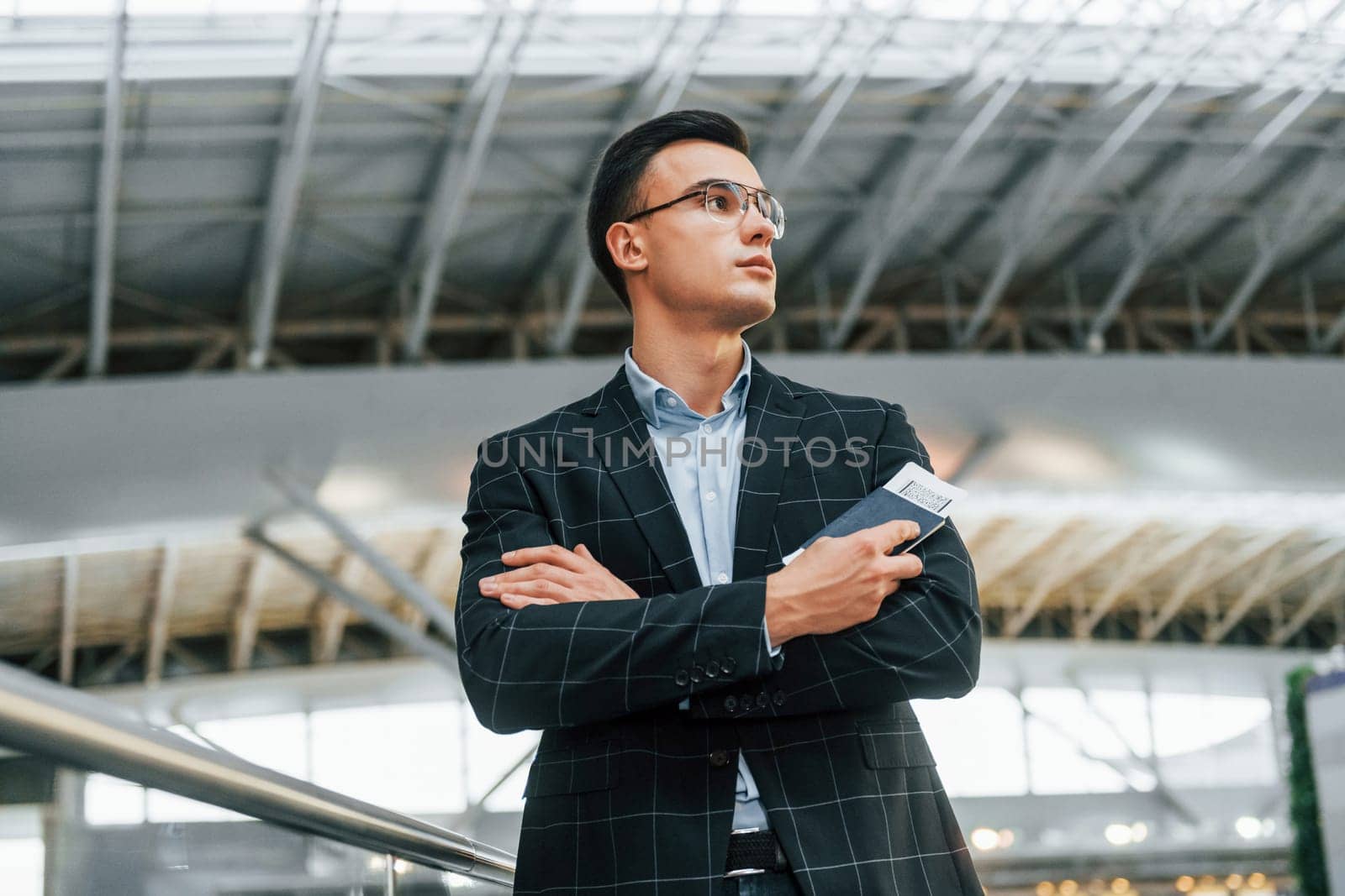 Serious look. Young businessman in formal clothes is in the airport at daytime by Standret