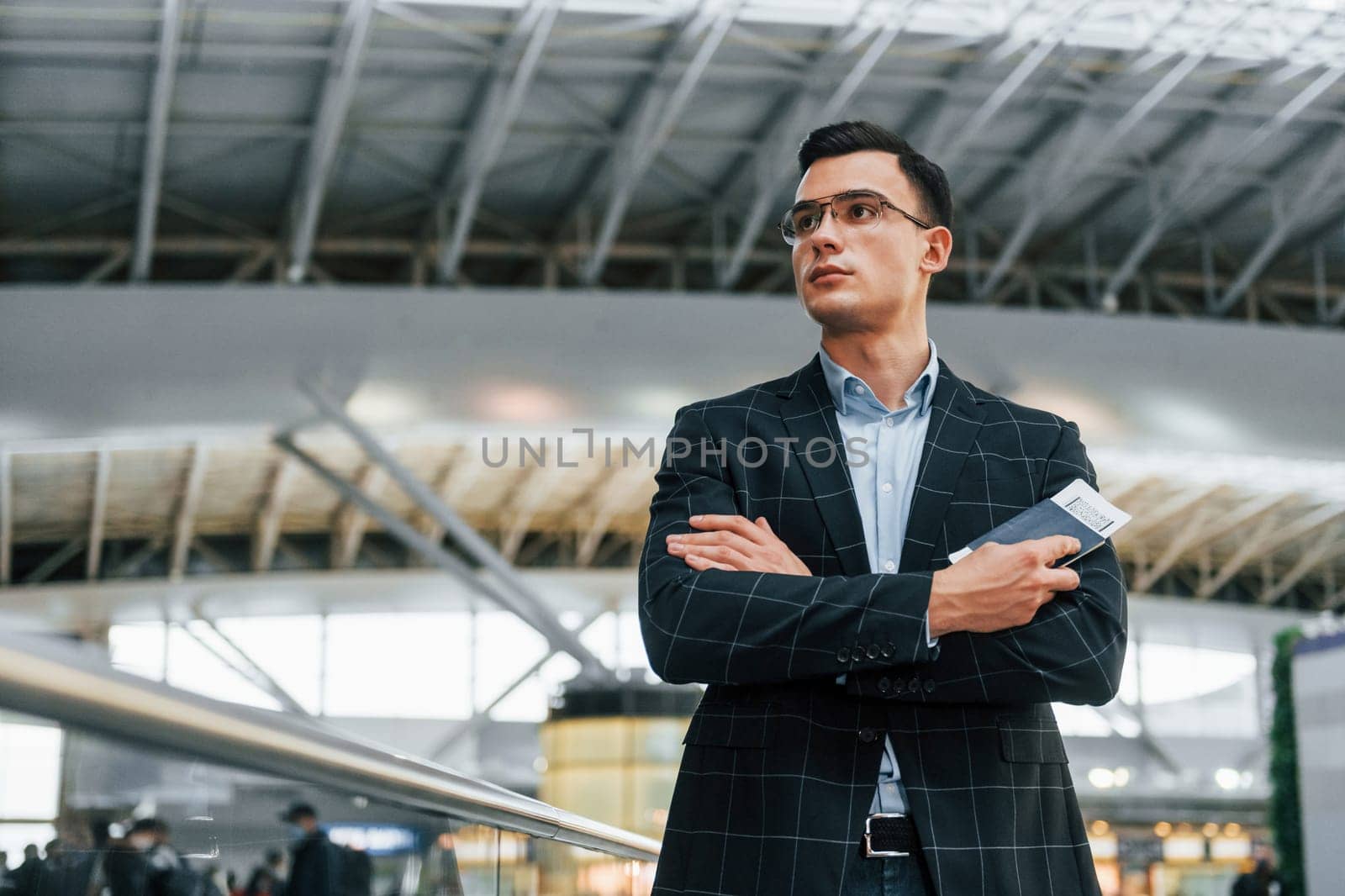 Serious look. Young businessman in formal clothes is in the airport at daytime by Standret