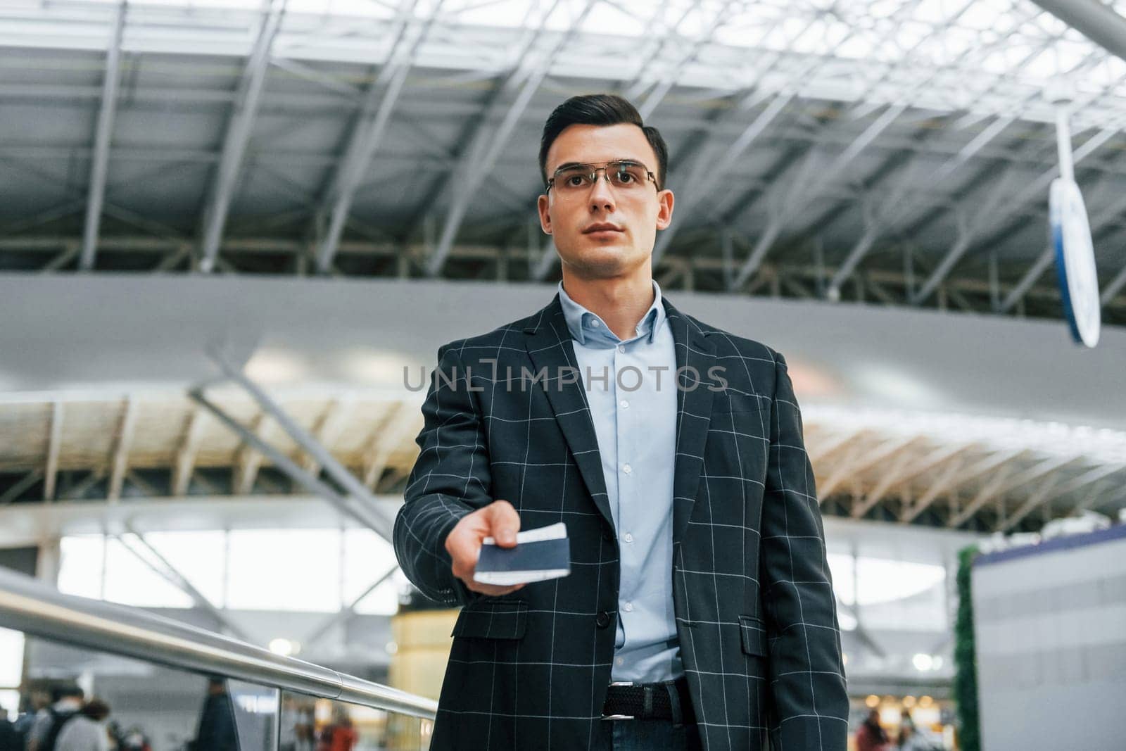 Serious look. Young businessman in formal clothes is in the airport at daytime by Standret