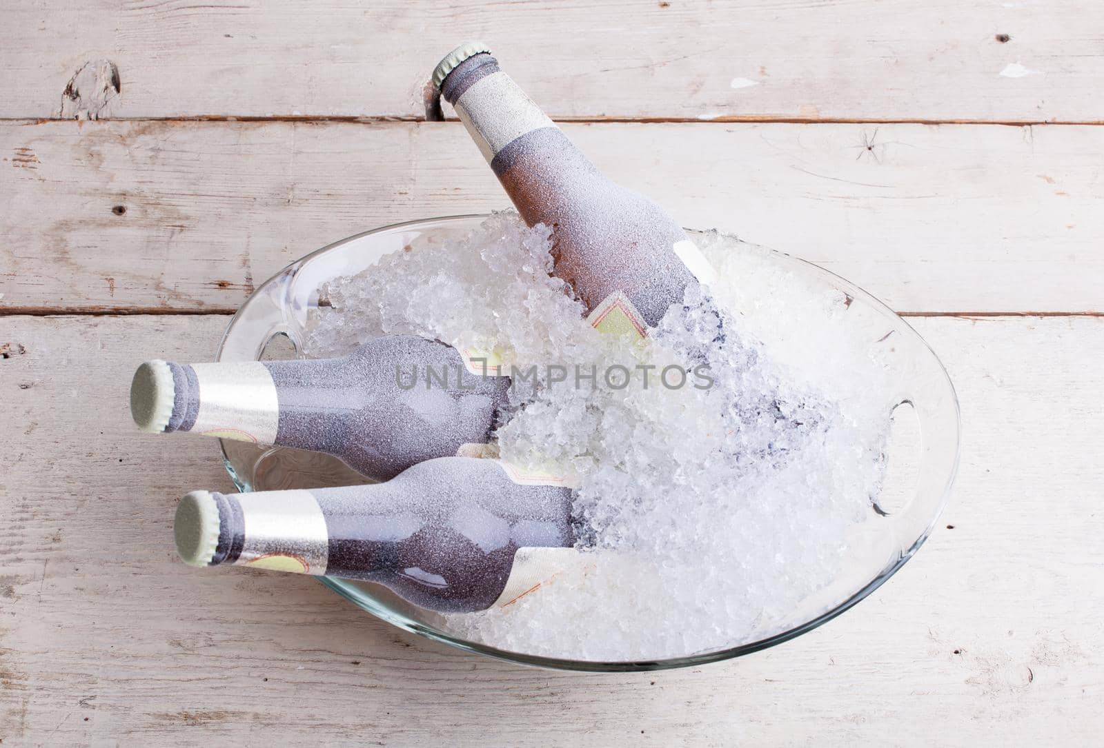 Three frozen glass bottles of beer immersed in the ice