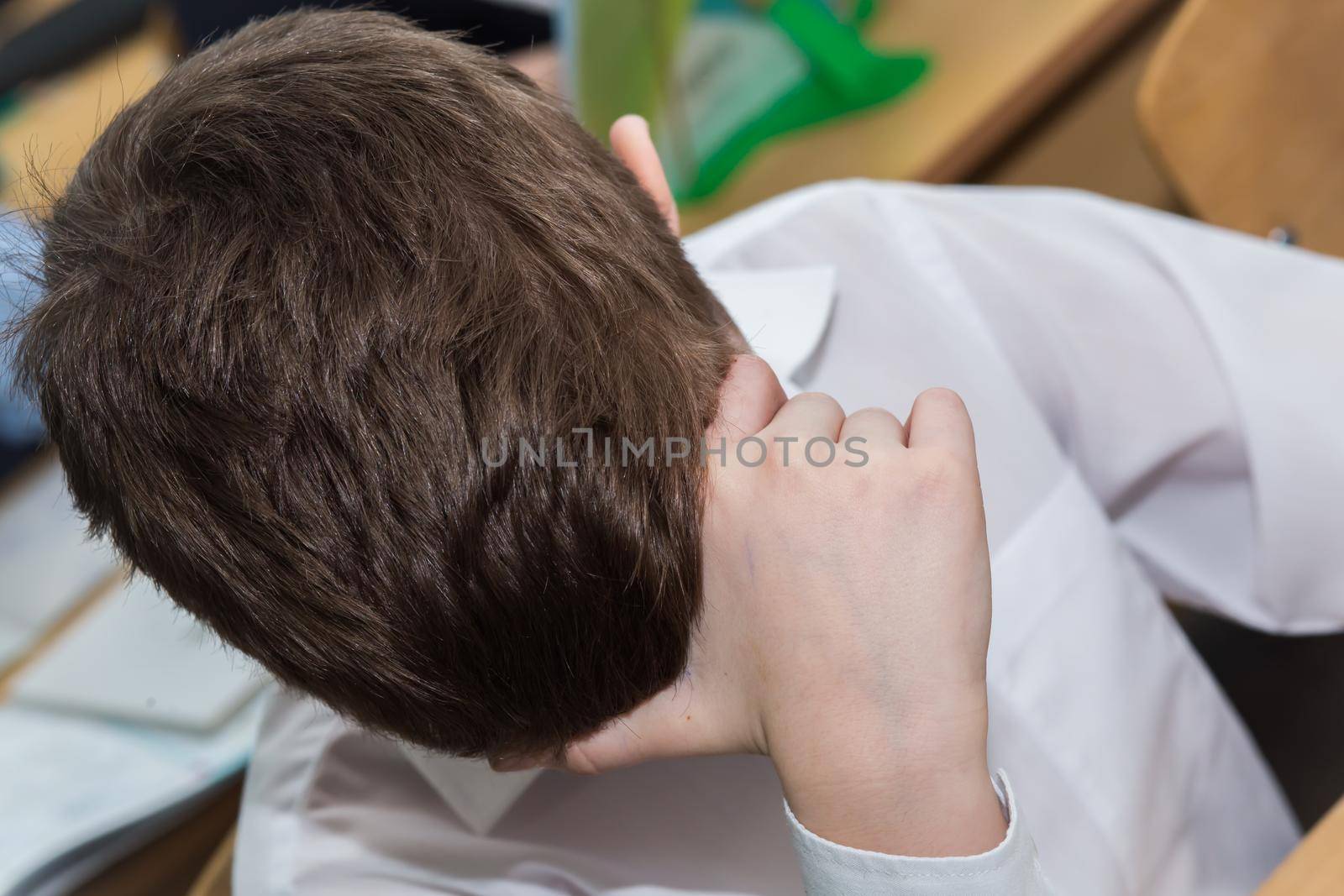 Close-up of a boy's hand supporting his head. A student at school sits at a desk and thinks or sleeps in class. Top view of the head of a man with a short haircut.