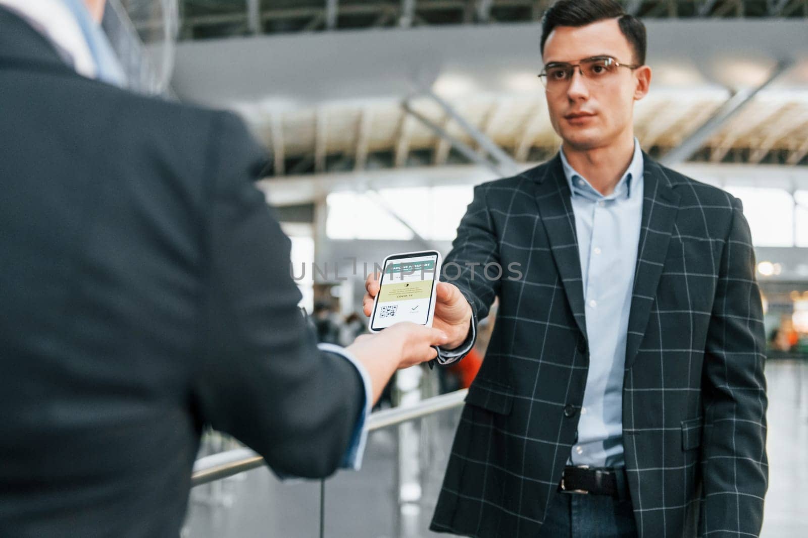 Passing through. Young businessman in formal clothes is in the airport at daytime.