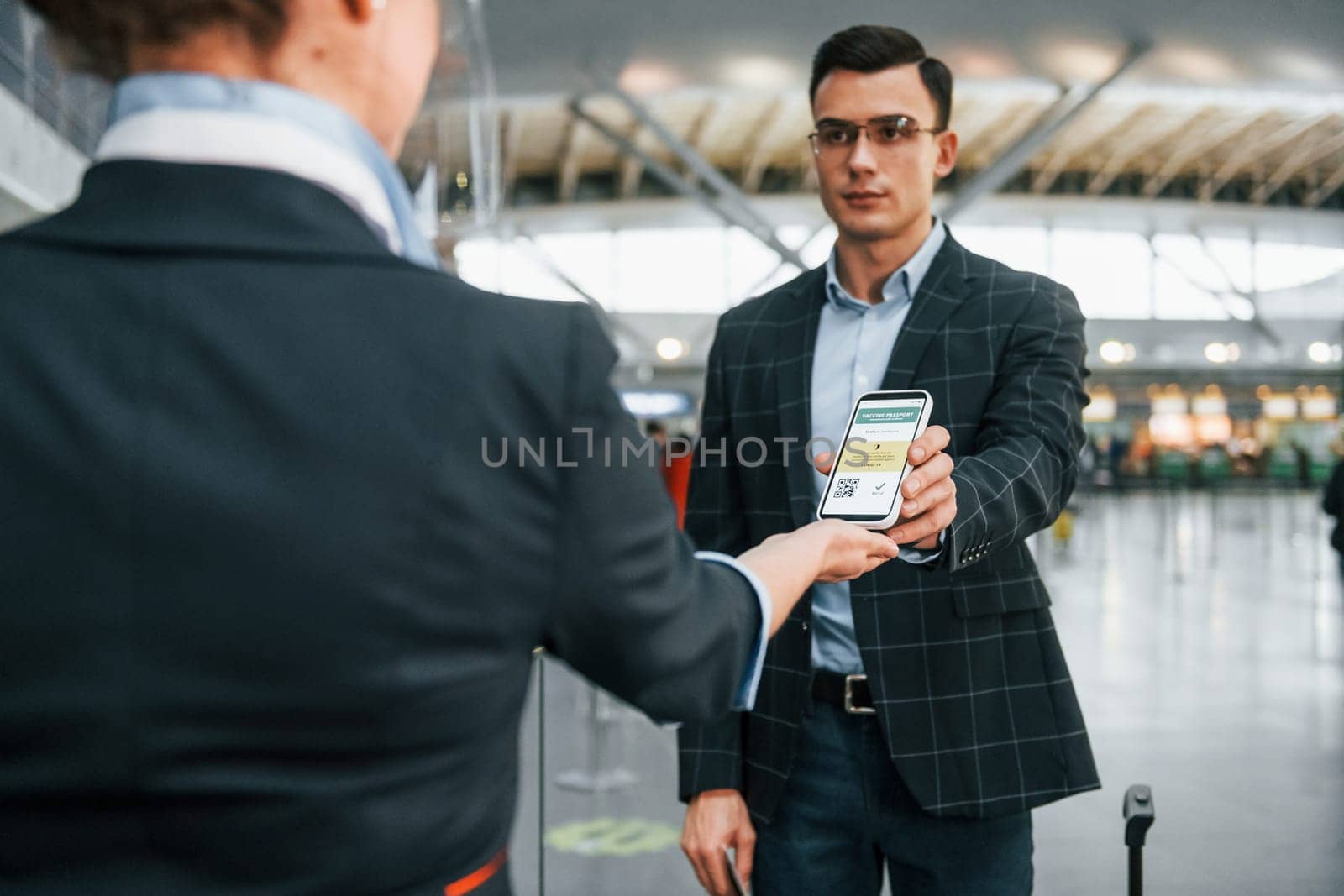 Passing through. Young businessman in formal clothes is in the airport at daytime.