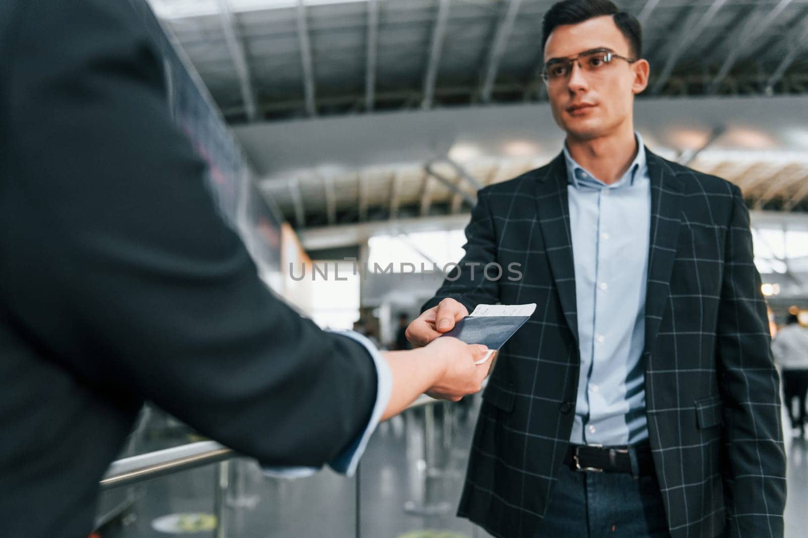 Holding and showing vaccination certificate. Young businessman in formal clothes is in the airport at daytime.