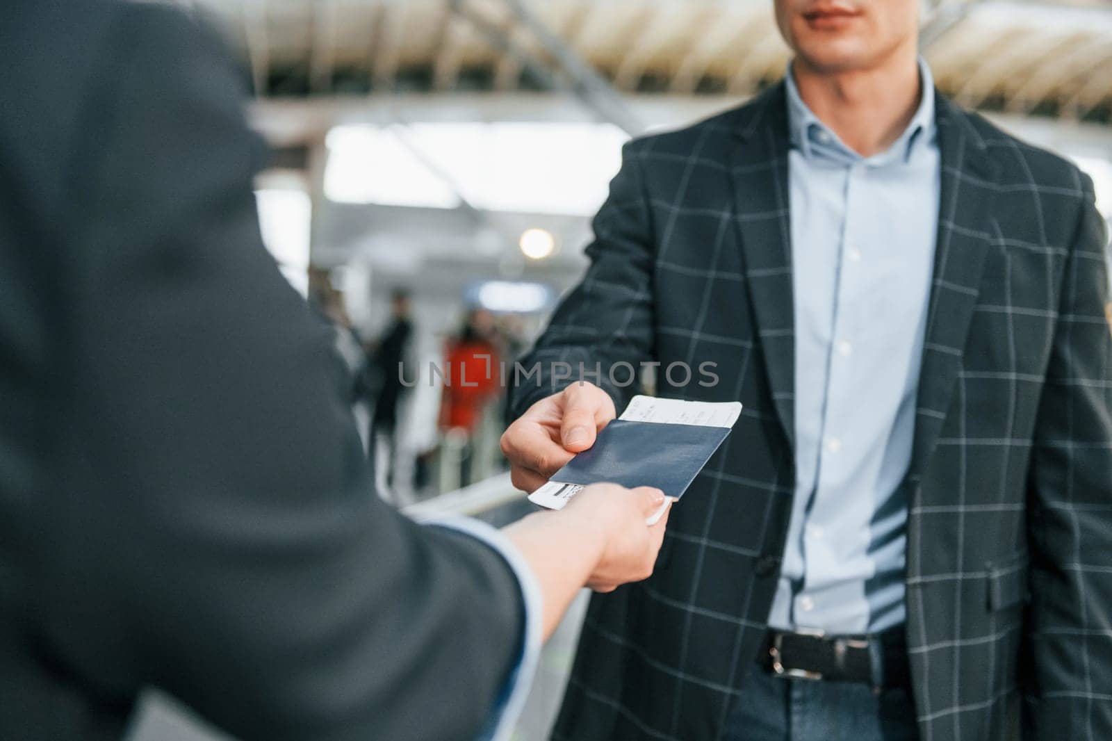 Working with documents. Young businessman in formal clothes is in the airport at daytime.