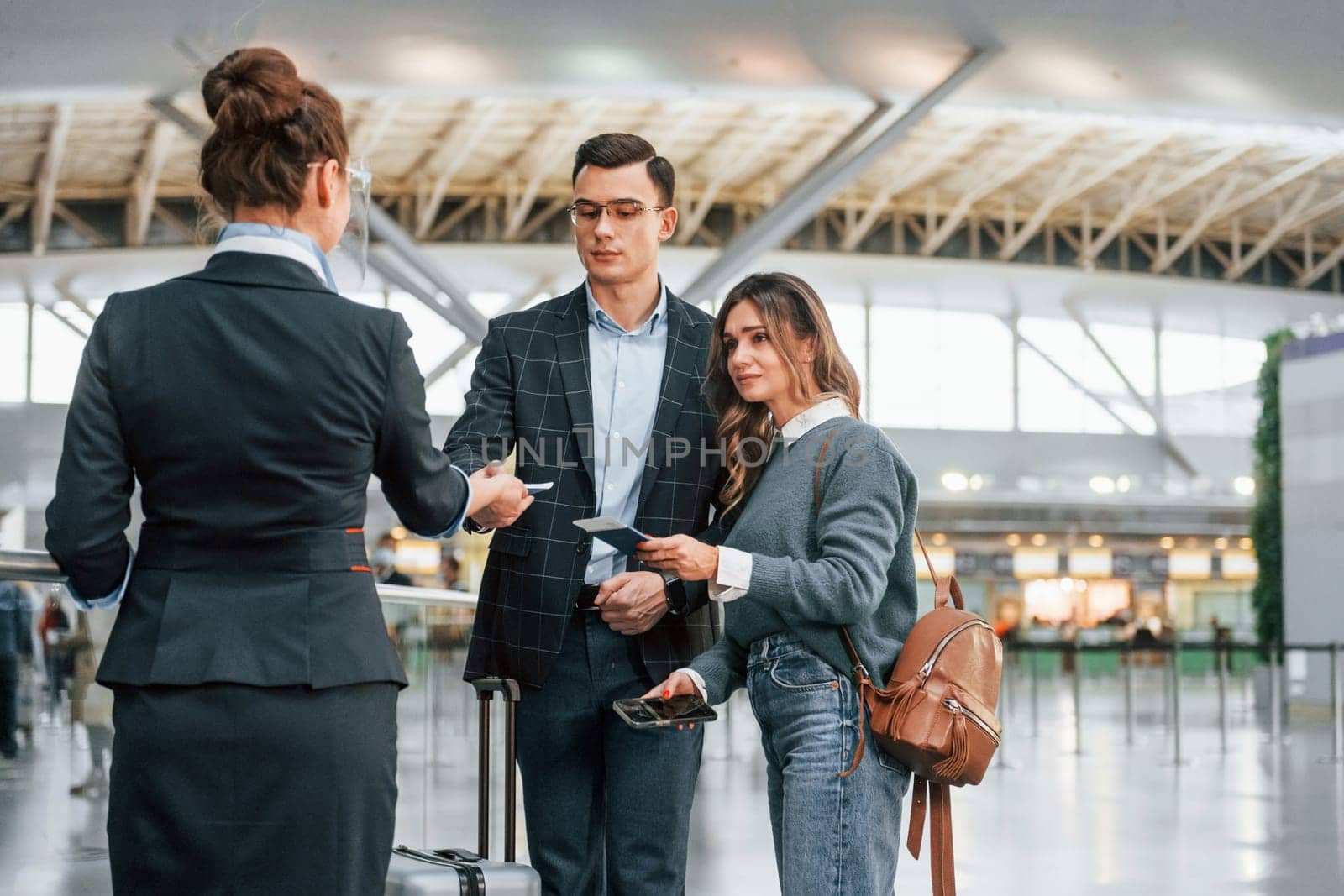 Giving the documents. Young couple is in the airport together.