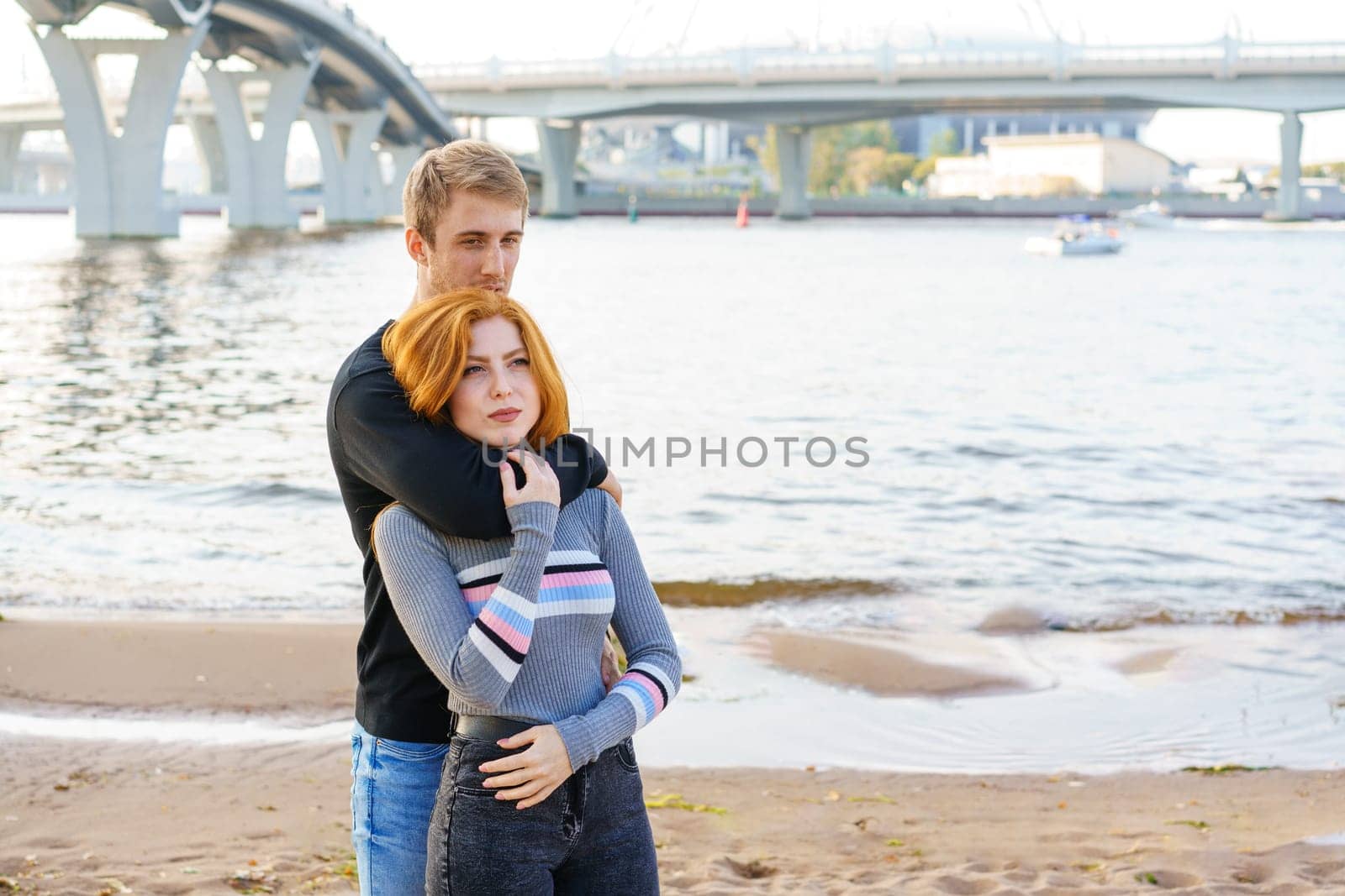 Young couple is standing on the river bank hugging by EkaterinaPereslavtseva